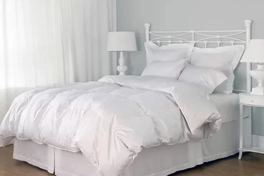 St Genève luxury down duvet on a white bed in a light airy room with white decorations and furnishings
