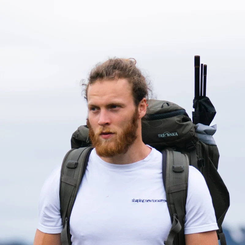 man with beard wearing backpack hiking in the mountains